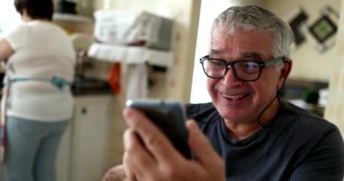 Man in 60s reacting positevely to good news on phone