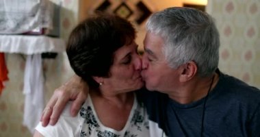 Married older couple kissing. Middle aged husband and wife smiling at camera