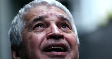 Yaşlı adamın yüzü umut ve inançla gökyüzüne bakıyor.