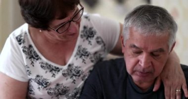 Preoccupied senior man seeking help and support. Wife consoling older husband