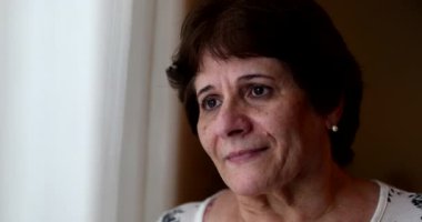 Umut dolu yaşlı kadın pencereden dışarı bakarak gözlerini açıyor. Düşünceli yaşlı bayan.