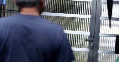 Yaşlı adam evin kapısını açarak dışarı çıkıyor.