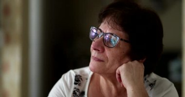 Portrait 60 year old woman daydreaming and looking at camera