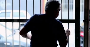 Senior man closing front entrance gate