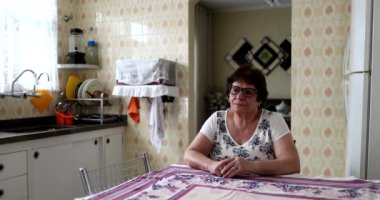 Thoughtful older woman sitting alone at kitchen table
