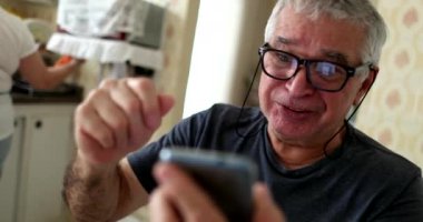 Senior man receiving good news on smartphone and celebrating with wife
