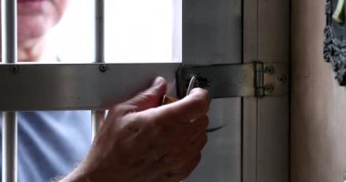 Man arriving home removing lock from home gate entrance