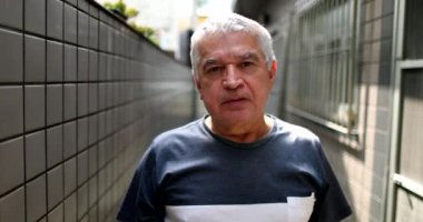 Middle aged man standing looking at camera with serious expression casual, real people