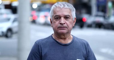 Portrait 60 year old senior man standing in city sidewalk