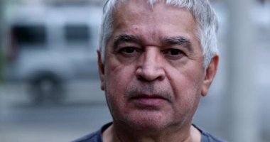 Middle-aged man portrait. Older unshaven person looking at camera outside