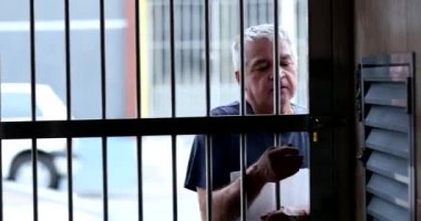 Senior man arriving home, person sliding metal gate entrance