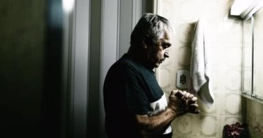 Old man praying to god with hands clenched together looking up during tragic circumstances