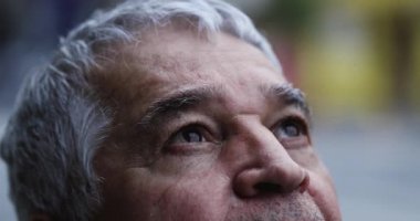 Yaşlı adam gözleri ve yüzü gökyüzüne bakıyor.