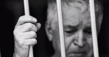 Çaresiz adam parmaklıklar ardında kilitli.