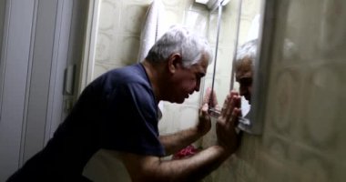 Stresli yaşlı adam banyo aynasının önünde. Orta yaş krizi