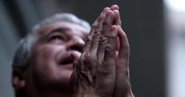 Senior man praying to God, believer raising hands asking for help