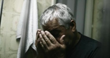 Woried old man with anxiety covering face with hand