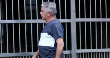 Senior man entering home opening front gate garage