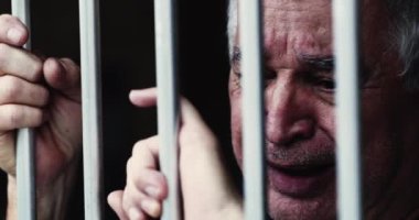Parmaklıklar ardındaki umutsuz yaşlı adam. Hapisteki kişi