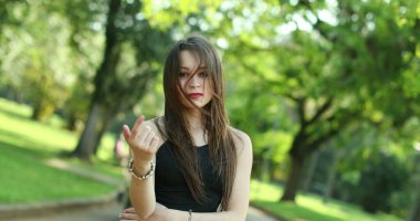 Parmak ve elle davet edilen çekici genç bir kadın. Milenyum kızı, davetkar izleyiciyi davet ediyor