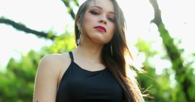 Çekici genç milenyum kadını. Açık hava parkında kameraya mercek ışığında poz veriyor.