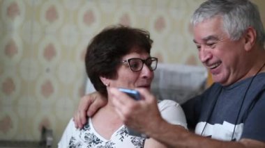 Happy older couple reacting to good news on cellphone. Senior husband sharing smartphone screen with wife