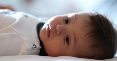 Baby lying in bed smiling close-up face