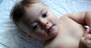 Sevimli bebek kameraya dokunmak için elini uzatıyor, tapılası bebek yüzü