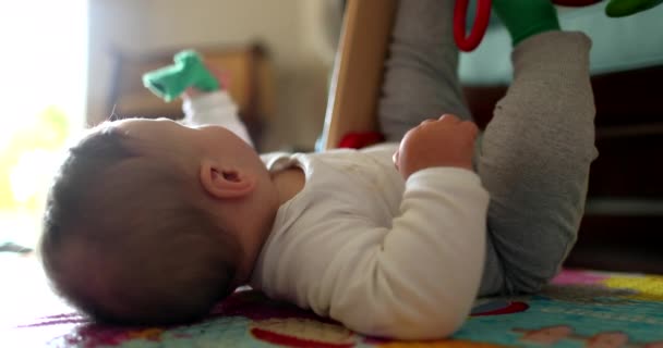 かわいい赤ちゃん寝そべって床遊びでおもちゃで遊ぶマット — ストック動画