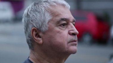Pensive older senior man standing outside in street in middle aged
