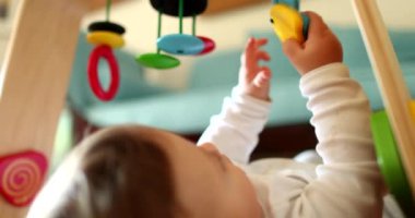 Bebek elleri oyuncak tutuyor, yakın plan bebek oyunları oynuyor ve yerde çocuk gelişimi var.