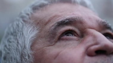 Senior man opening eyes looking at sky with hope and faith