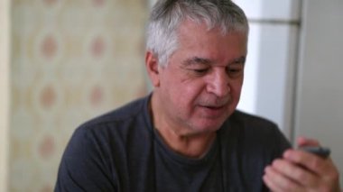 Happy casual older man receiving good news on mobile phone
