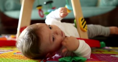 Bebek elleri oyuncak tutuyor, yakın plan bebek oyunları oynuyor ve yerde çocuk gelişimi var.