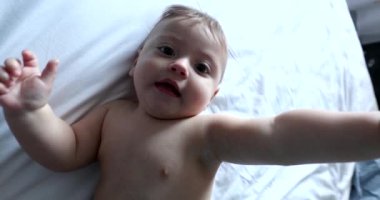 Baby grabbing camera lens. POV of dad filming toddler infant in bed grabs camera looking inside