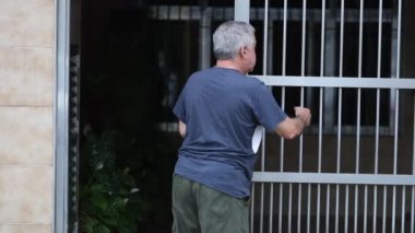 Older man closing home entrance gate