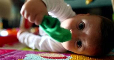 Çorapla oynayan şirin bir bebek, ağzına giysi koyan sevimli bir bebek portresi.