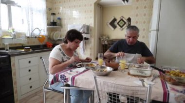 Casual husband and wife eating lunch together at home