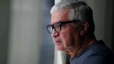 Older man peeking outside through window