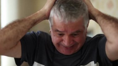 Senior man celebrating success reacting positively to news on smartphone