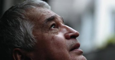 Pensive man in 60s feeling relief from anxiety. Older person looks at sky