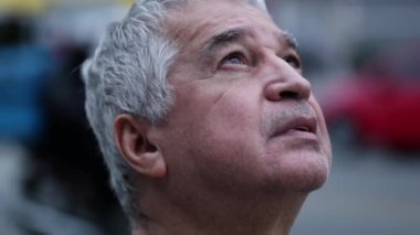 Older man face opening eyes in contemplation loooking up at the sky with hope and faith