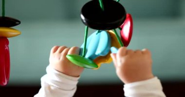 Bebek elleri oyuncak tutuyor, çocuk geliştirme oyuncaklarıyla yakın plan bebek oyunları oynuyor.