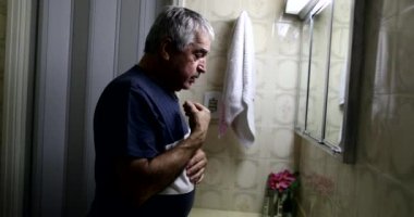 Old man asking God guidance and help. Senior doing cross sign and praying in bathroom