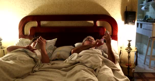 Ηλικιωμένο Ζευγάρι Ξαπλωμένο Στο Κρεβάτι Χρησιμοποιώντας Κινητό Τηλέφωνο Πριν Τον — Αρχείο Βίντεο