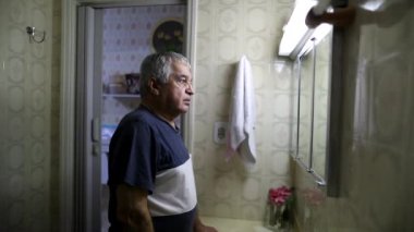 Man staring at bathroom mirror suffering anxiety