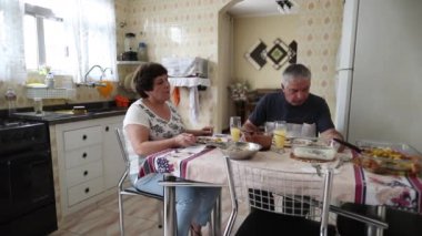Older couple eating lunch at kitchen home. Casual seniors together in domestic life