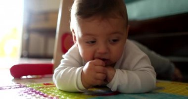 Sevimli bebek paspasın üzerinde yatıyor oyuncakla oynuyor, çocuk gelişimi