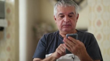 Older man putting reading glasses using cellphone