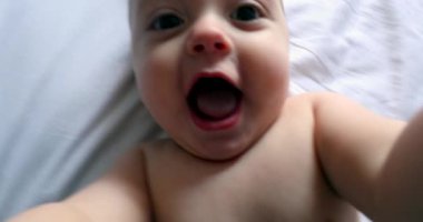 Baby grabbing camera lens. POV of dad filming toddler infant in bed grabs camera looking inside